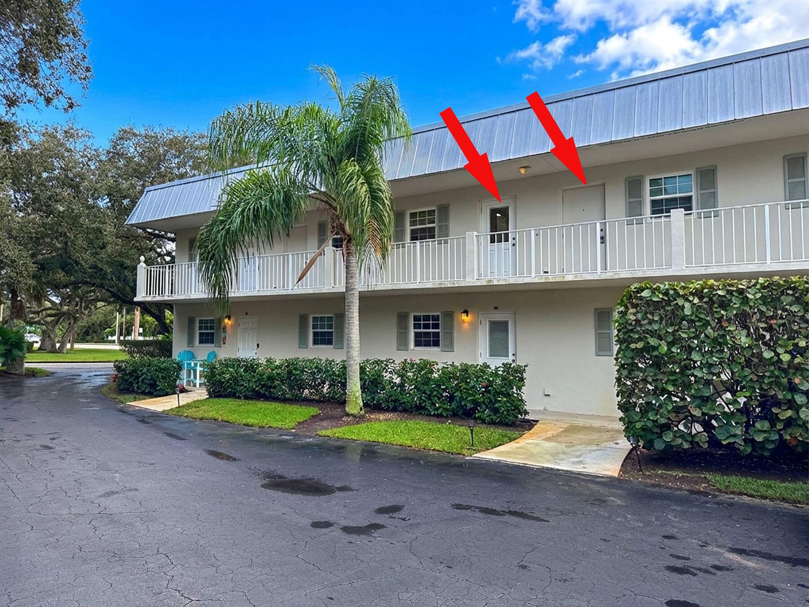 A two-story apartment building exterior features a white balcony with two doors and palm trees — 900 Jasmine Lane # 9a, Vero Beach FL 32963, VERO BEACH, FL
