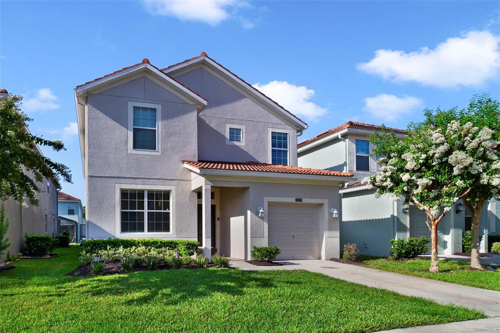 A two-story suburban house with a light-colored stucco exterior, a tiled roof, and a garage — 8928 BISMARCK PALM ROAD, KISSIMMEE, FL