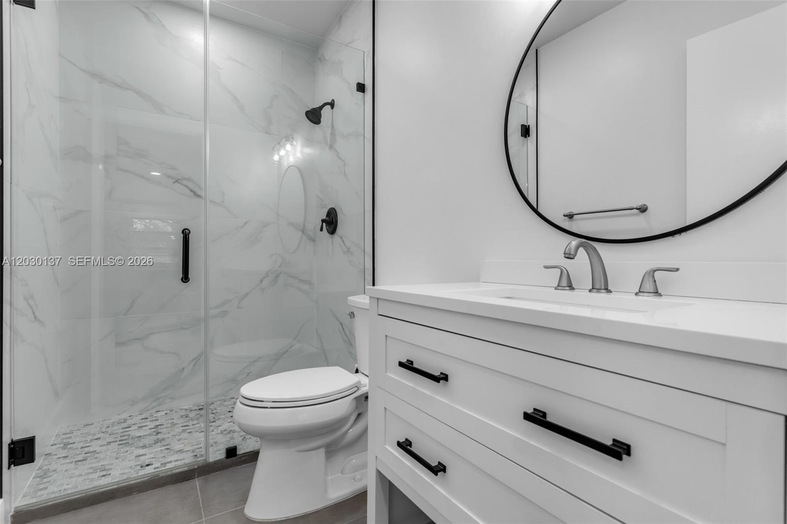 A modern bathroom features a glass-enclosed shower, a white vanity, and a round mirror — 13726 SW 90th Ave # 28, Miami FL 33176, MIAMI, FL