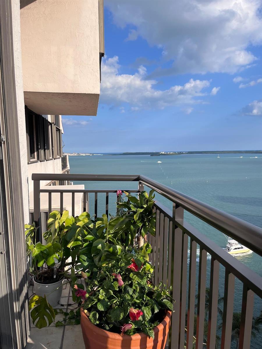 A balcony with potted plants overlooks a large body of water under a blue sky — 540 Brickell Key Drive # 1721, Miami FL 33131, MIAMI, FL