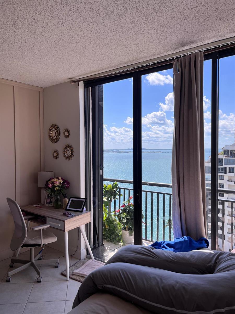 A bedroom with a desk, a bed, and a balcony overlooking a large body of water — 540 Brickell Key Drive # 1721, Miami FL 33131, MIAMI, FL