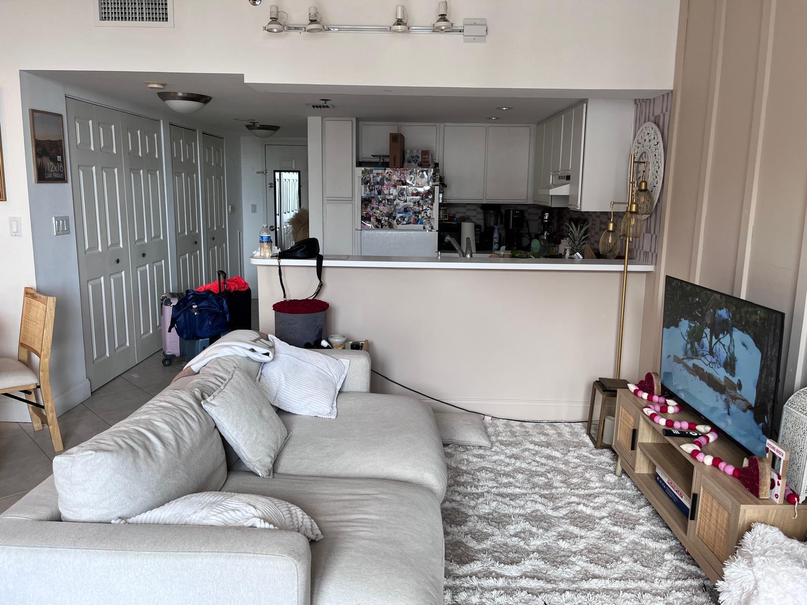 A living room with a light-colored sofa, area rug, and television faces an open kitchen — 540 Brickell Key Drive # 1721, Miami FL 33131, MIAMI, FL