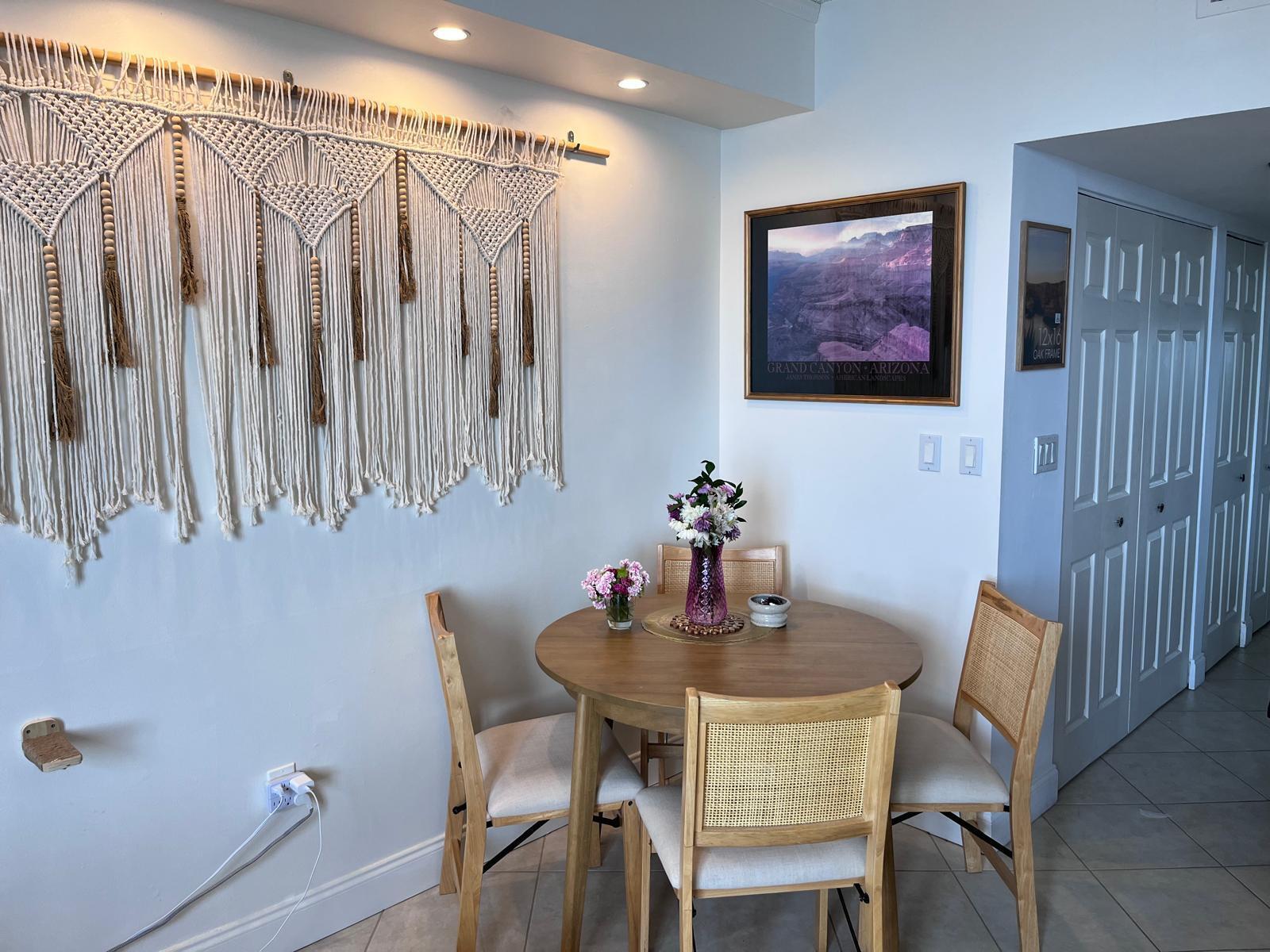 A dining area features a round wooden table, four cane-back chairs, and a large macramé wall hanging — 540 Brickell Key Drive # 1721, Miami FL 33131, MIAMI, FL