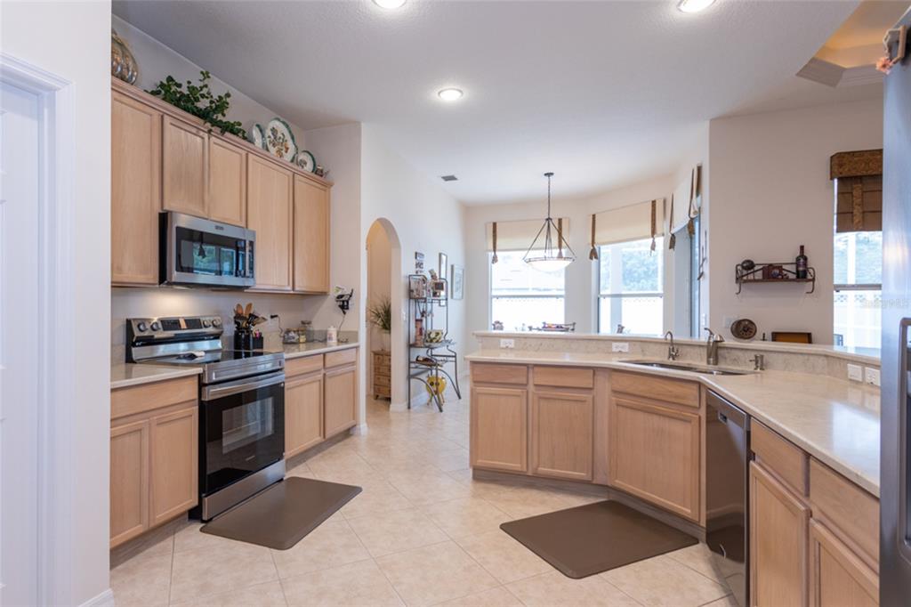 A kitchen with light wood cabinets, stainless steel appliances, and tile flooring — 4 EAGLE PLACE, PALM COAST, FL