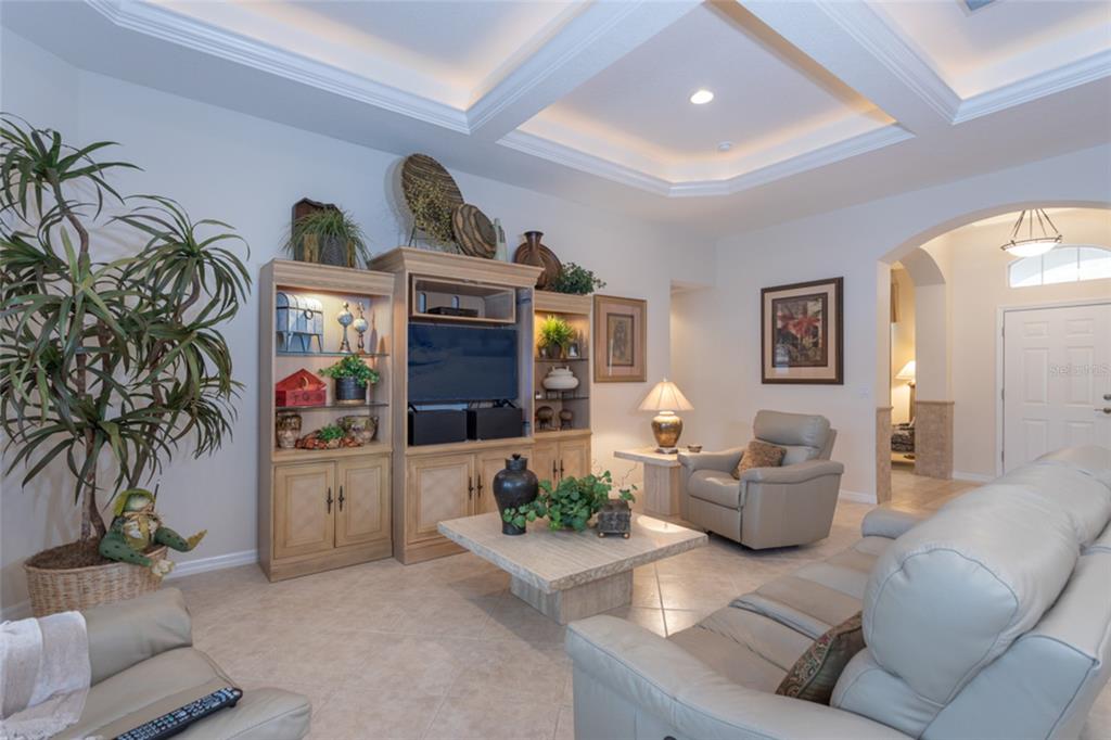 A living room features a large entertainment center, a stone coffee table, and leather seating — 4 EAGLE PLACE, PALM COAST, FL
