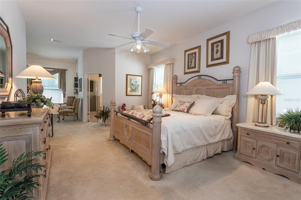 A bedroom features a wooden bed frame, matching furniture, carpeted floors, and a ceiling fan — 4 EAGLE PLACE, PALM COAST, FL