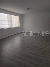 An empty room features light-colored wood-look flooring, white walls, and a large window with blinds — 230 MONROE AVENUE, BROOKSVILLE, FL
