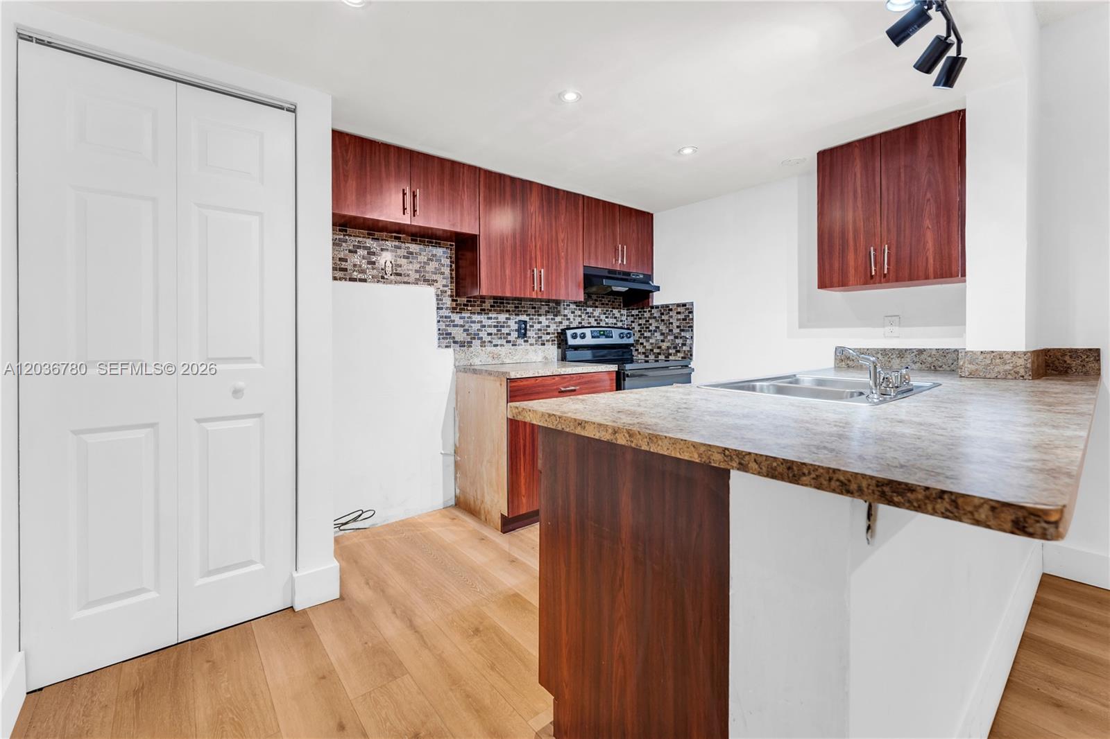 A kitchen features wood-toned cabinets, a mosaic tile backsplash, and a laminate countertop island — 5653 Blueberry CT # 2, Lauderhill FL 33313, LAUDERHILL, FL