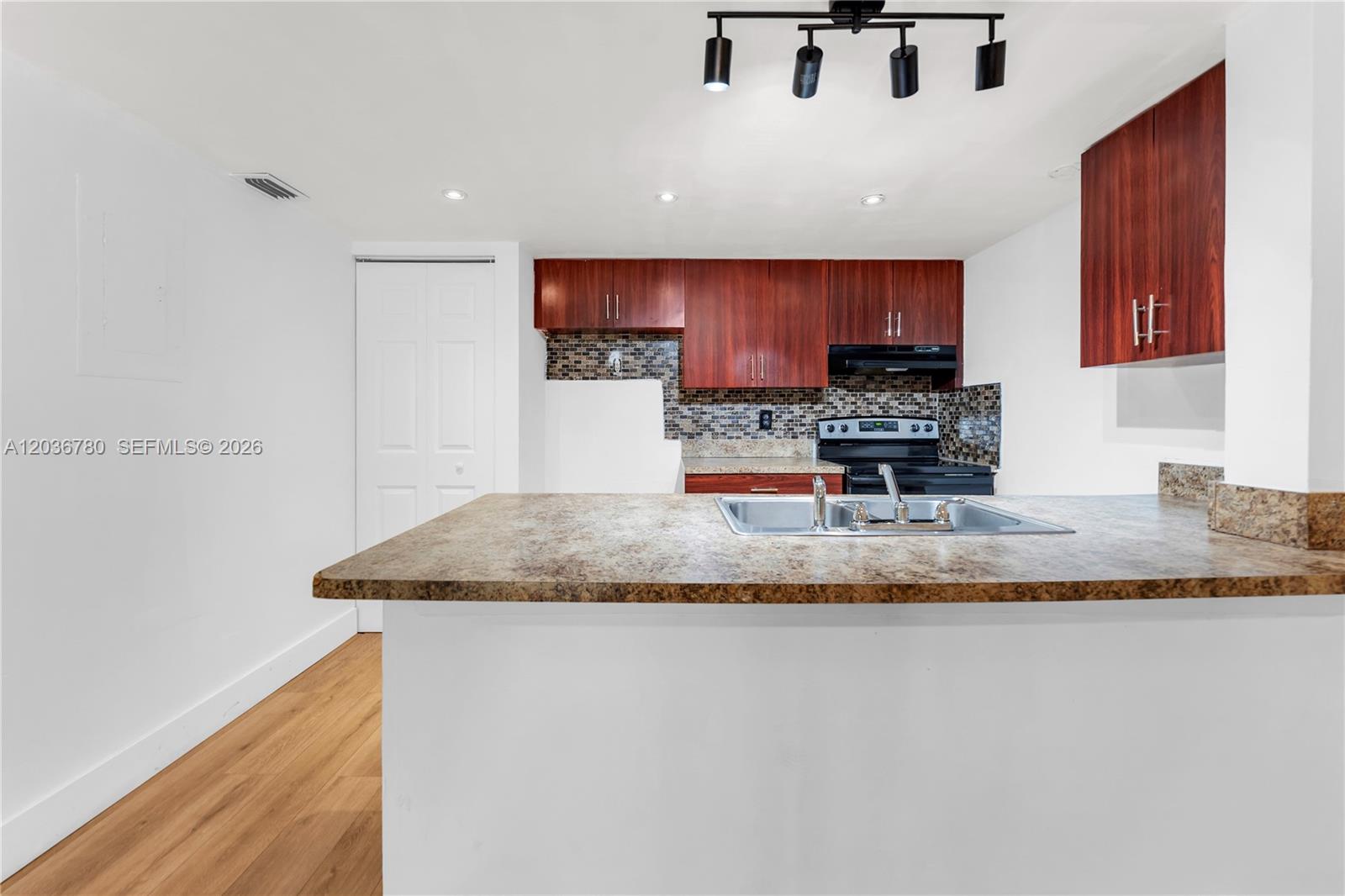 A kitchen features dark wood cabinets, a laminate countertop, and a stainless steel sink — 5653 Blueberry CT # 2, Lauderhill FL 33313, LAUDERHILL, FL