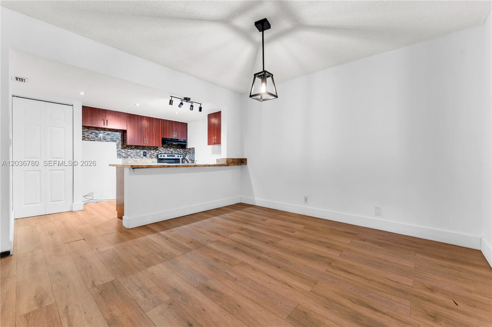 A dining area with wood-look flooring and a pendant light overlooks an open kitchen — 5653 Blueberry CT # 2, Lauderhill FL 33313, LAUDERHILL, FL