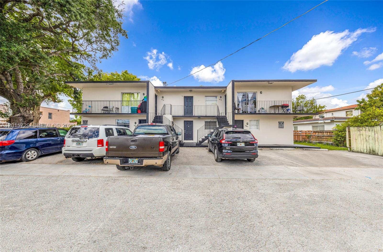 A two-story apartment building features exterior staircases, balconies, and a gravel parking lot — 1800 NW 19th Ter, Miami FL 33125, MIAMI, FL