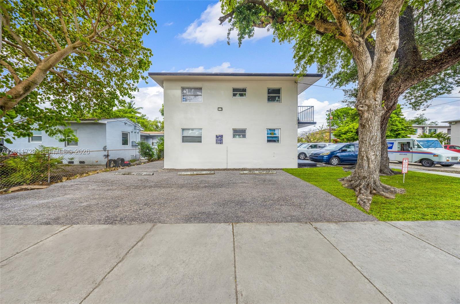 A two-story apartment building features a gravel parking area and a large tree in front — 1800 NW 19th Ter, Miami FL 33125, MIAMI, FL
