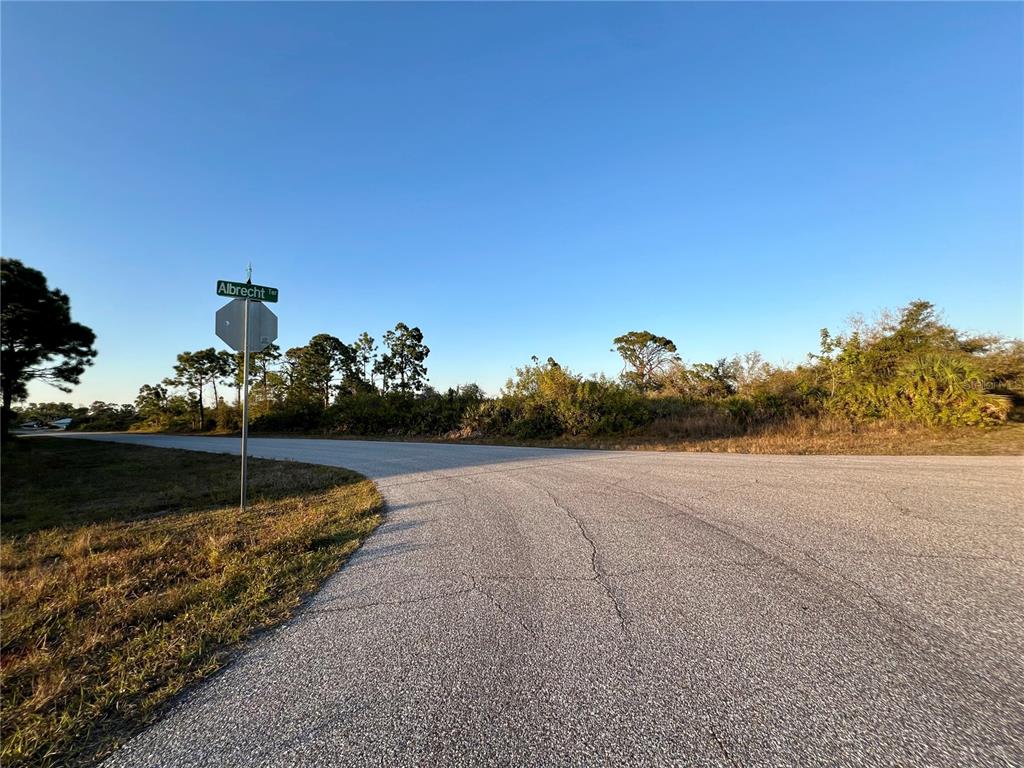A paved road curves past a street sign labeled Albrecht Ter next to a wooded lot — 12332 ALBRECHT TERRACE, PORT CHARLOTTE, FL