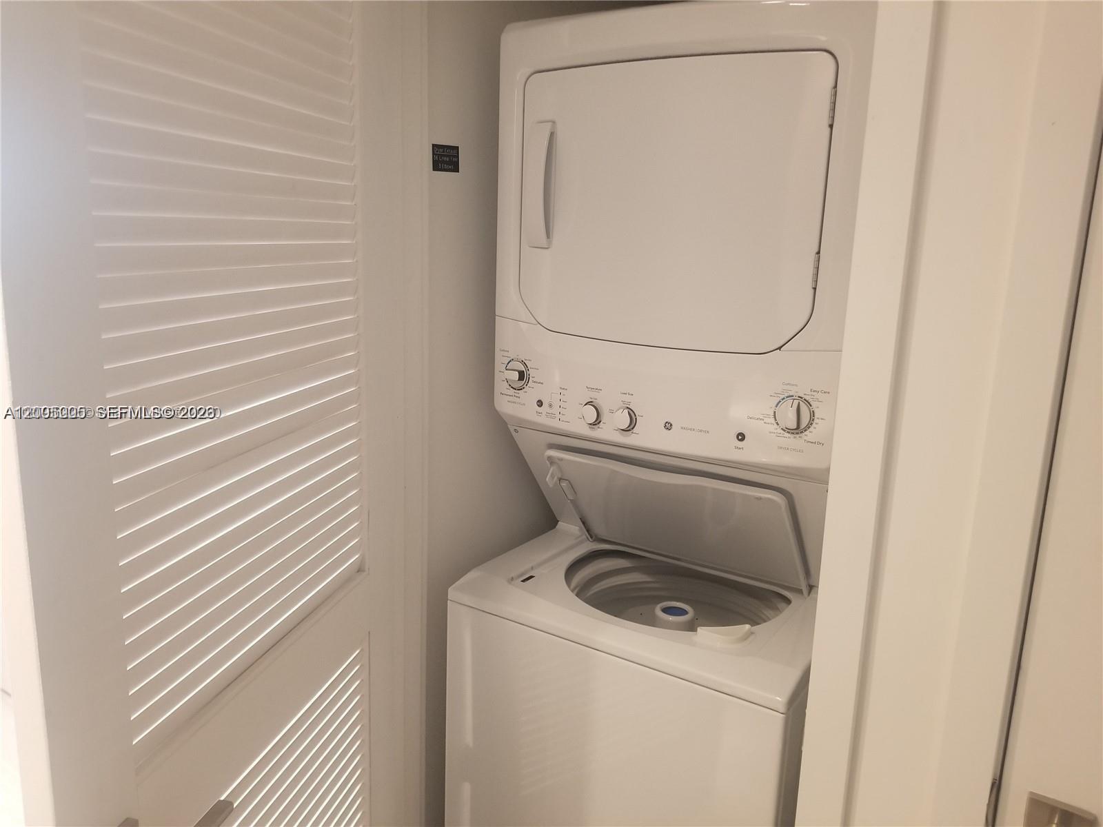 A white stacked washer and dryer unit is installed in a small laundry closet — 121 NE 34 St # 2215, Miami FL 33137, MIAMI, FL