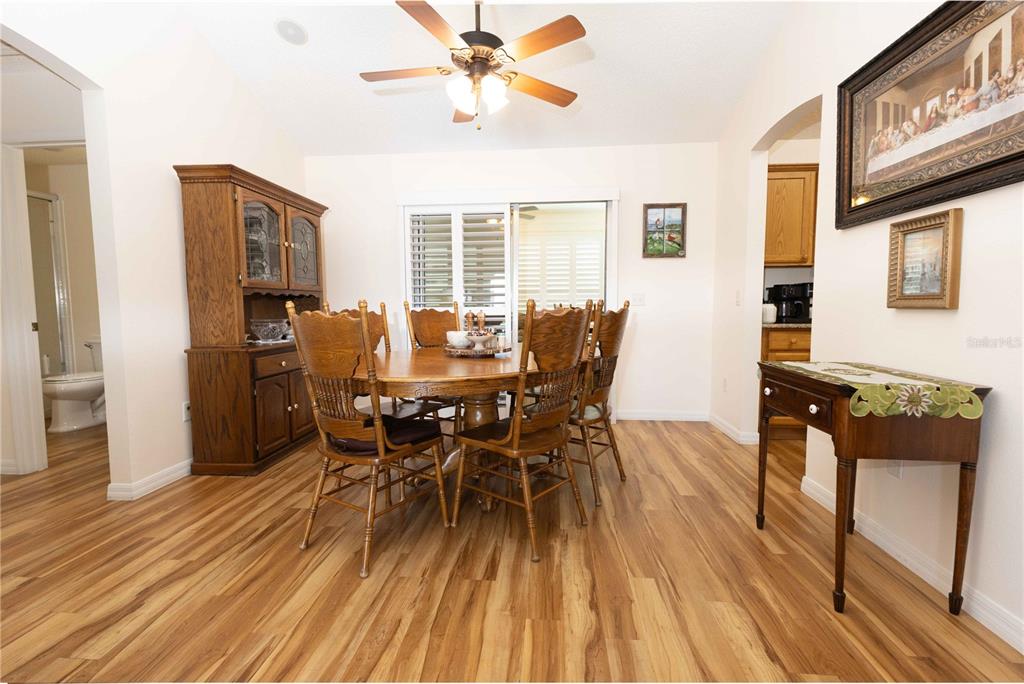 A dining room features wood-look flooring, a wooden table with chairs, and a matching hutch — 2706 MORVEN PARK WAY, THE VILLAGES, FL