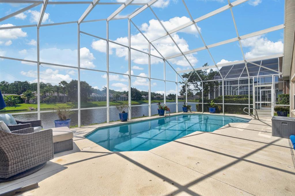 A screened-in patio features a swimming pool overlooking a lake with outdoor furniture — 1234 CROWN POINTE LANE, ORMOND BEACH, FL