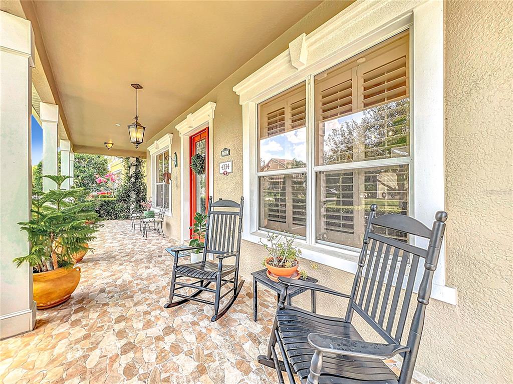 A covered front porch features stone flooring, two rocking chairs, and a red front door — 4334 TOLKIEN STREET, ORLANDO, FL