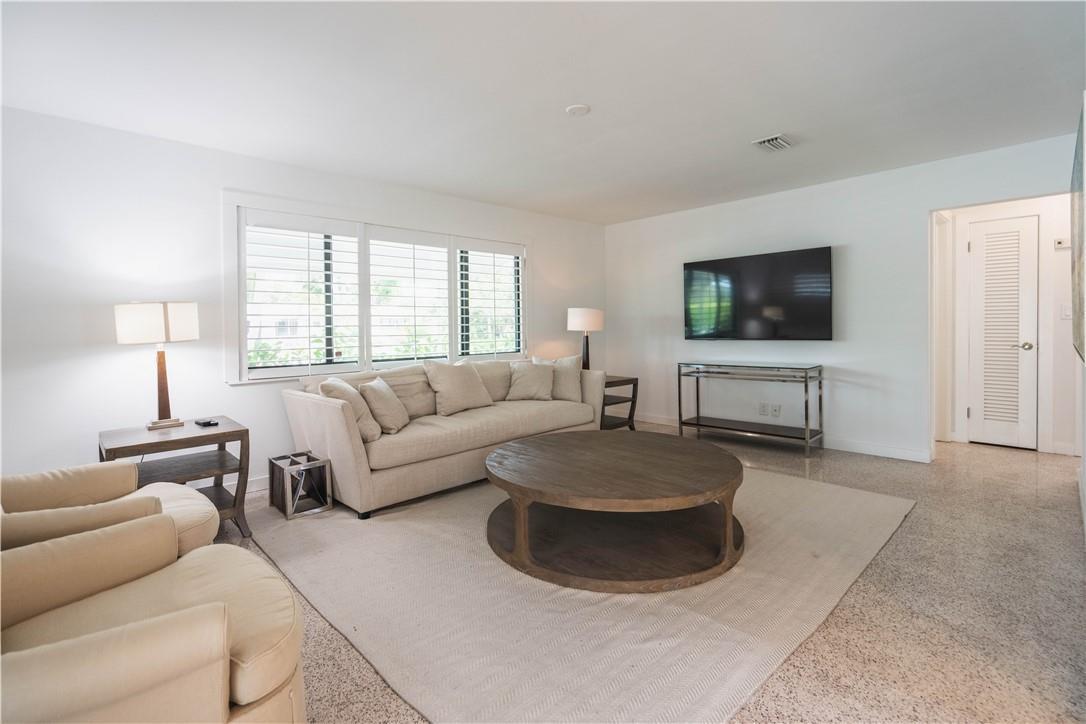 A living room features a beige sofa, round wooden coffee table, and wall-mounted television — 240 NE 25th Avenue, Pompano Beach FL 33062, POMPANO BEACH, FL