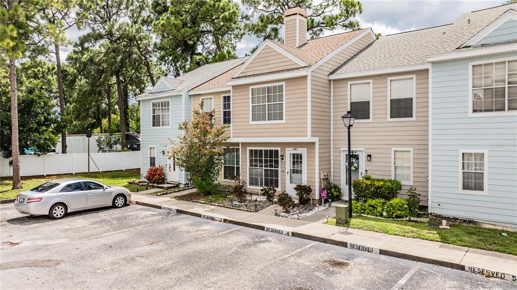 A row of multi-story townhouses with light-colored siding and reserved parking spaces in front — 6780 121ST AVENUE UNIT 3, LARGO, FL