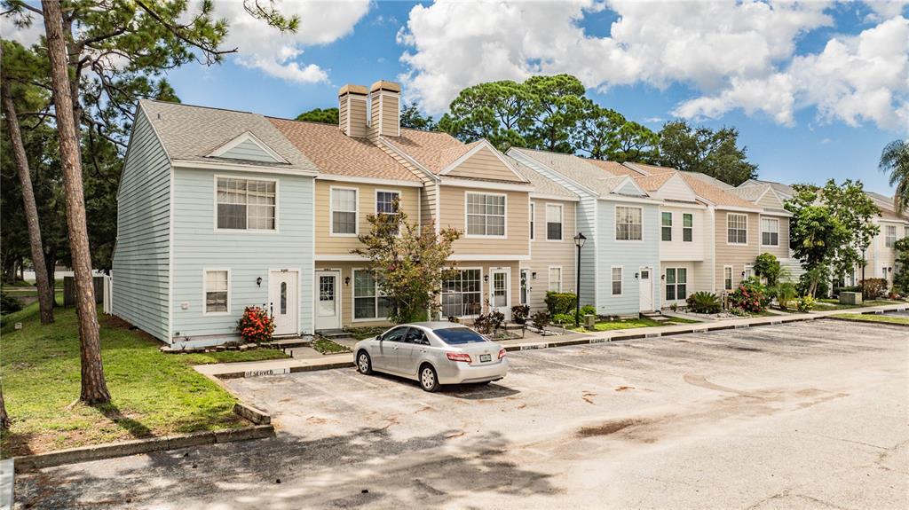 A row of multi-story townhomes with light-colored siding and a paved parking lot in front — 6780 121ST AVENUE UNIT 3, LARGO, FL