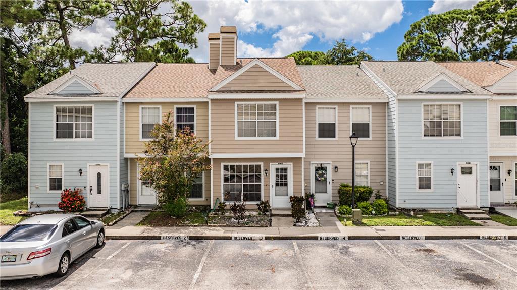 A row of multi-story townhomes with light blue and tan siding and reserved parking spaces — 6780 121ST AVENUE UNIT 3, LARGO, FL