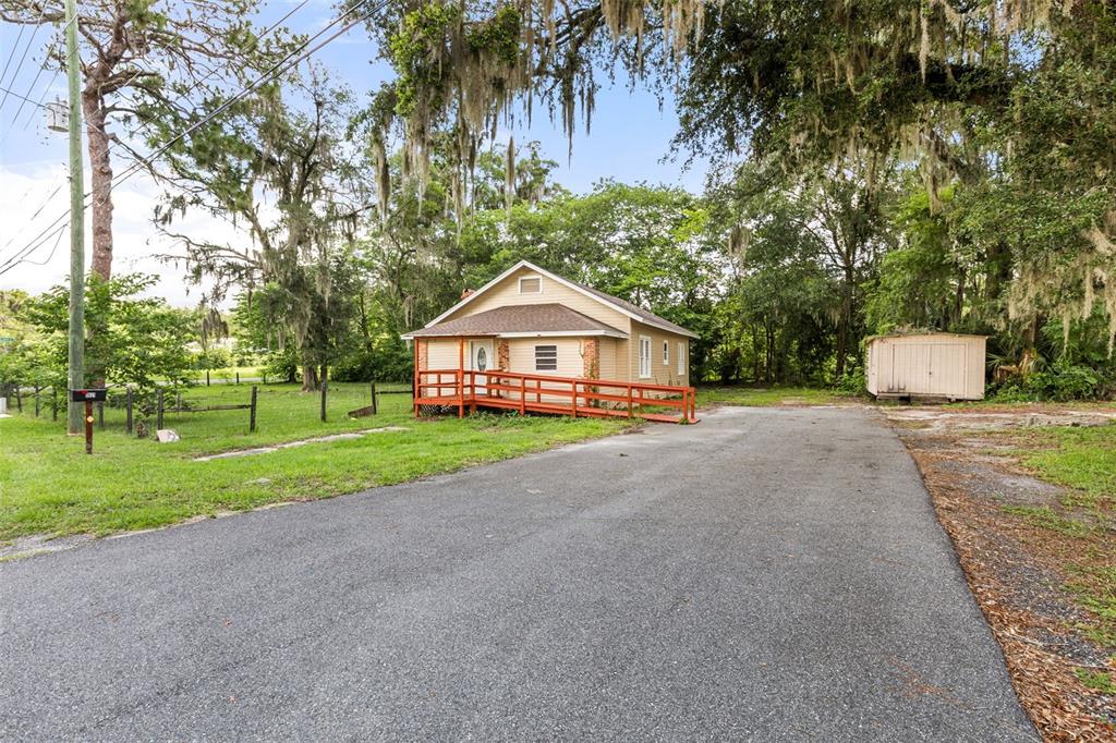 A tan house with a red wooden ramp sits on a lot with trees — 1921 NE 8TH ROAD, OCALA, FL