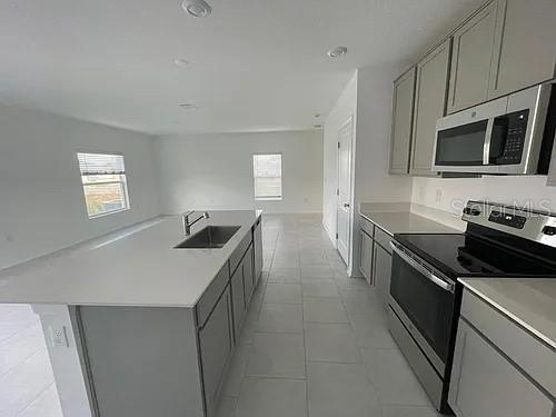 A modern kitchen features gray cabinets, stainless steel appliances, and a large white island — 642 BELL PRAIRIE CIRCLE, LAKE WALES, FL