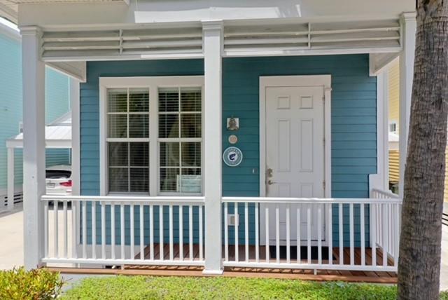 A blue house exterior features a white front porch with a railing and a door — 102 Anglers Way, Islamorada FL 33036, ISLAMORADA, FL