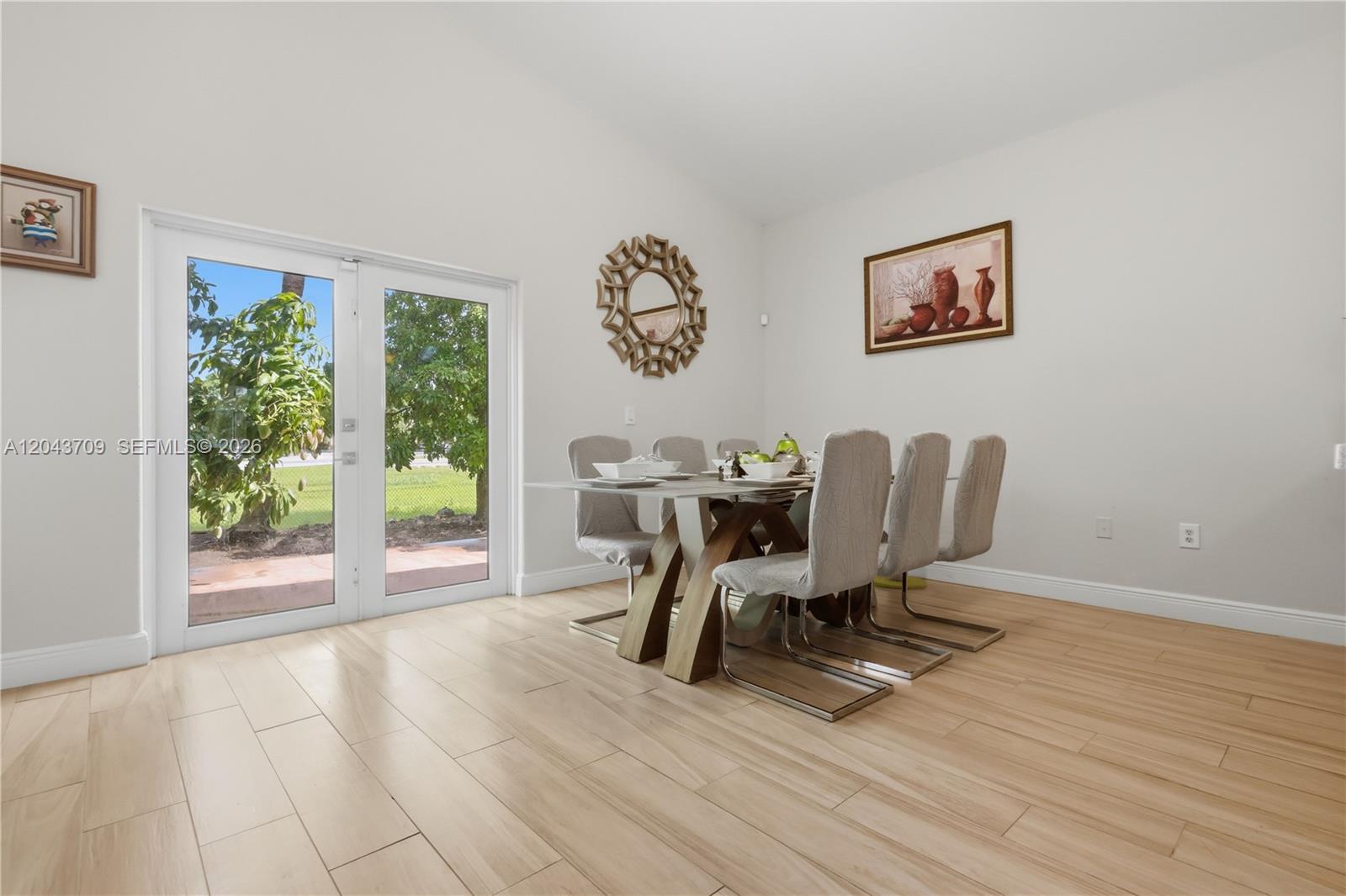 A dining room features a glass-topped table, six upholstered chairs, and glass patio doors — 610 SE 12th Ter, Homestead FL 33033, HOMESTEAD, FL