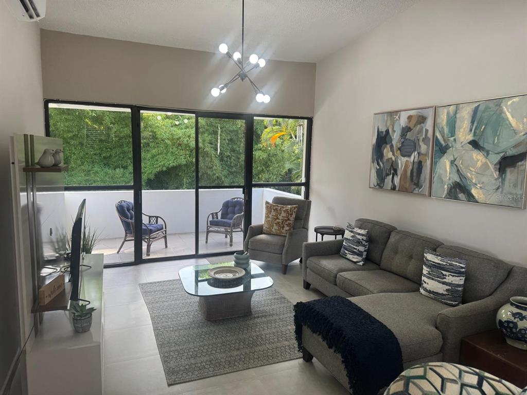 A living room with a gray sectional, glass coffee table, and sliding doors to a balcony — G24 CARRETERA 834 KM 2.4 BO. HATO NUEVO, GUAYNABO, PR