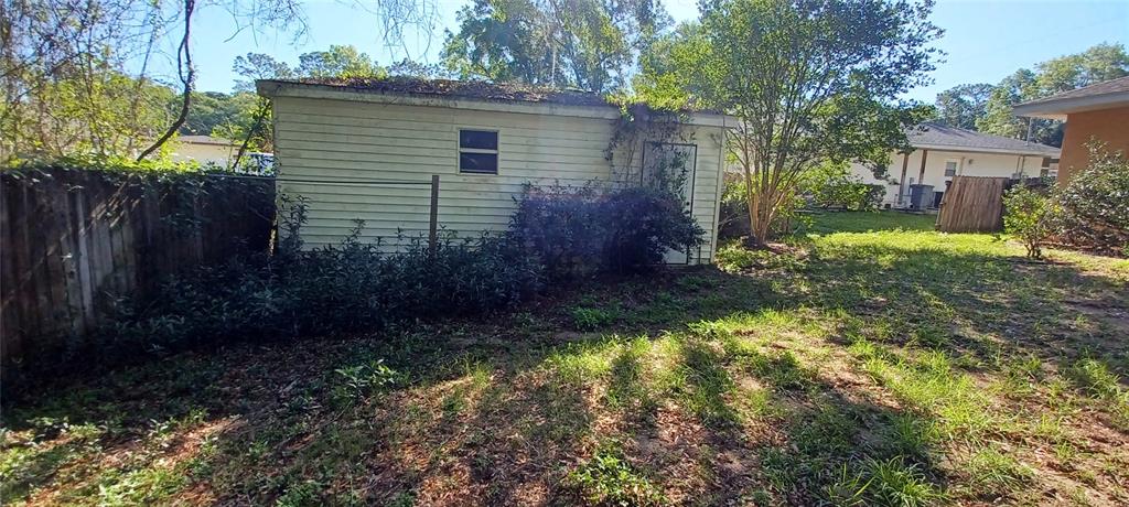 A detached shed with light-colored siding sits in a backyard next to a wooden fence — 6521 E GRAYSON STREET, INVERNESS, FL