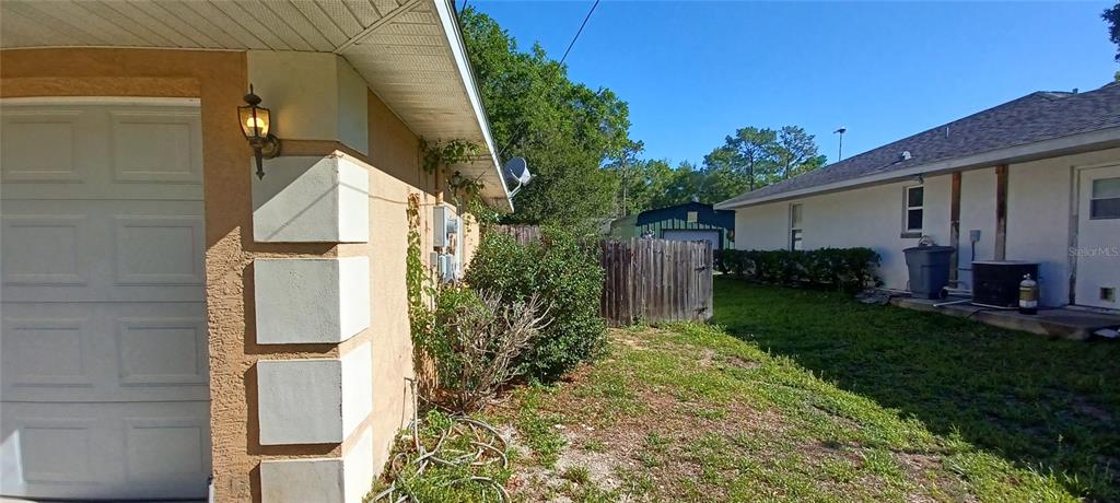 The exterior view shows a side yard between two houses with a wooden fence — 6521 E GRAYSON STREET, INVERNESS, FL
