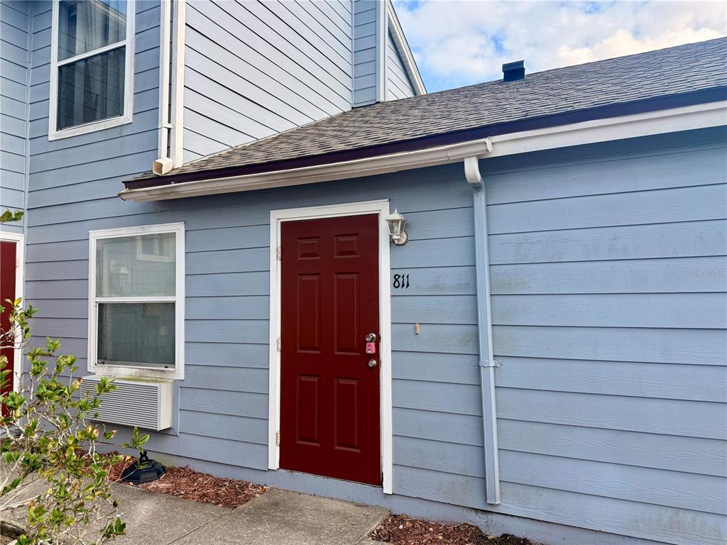 A red front door with the number 811 is set into a light blue exterior wall — 811 ORCHID DRIVE, DAVENPORT, FL