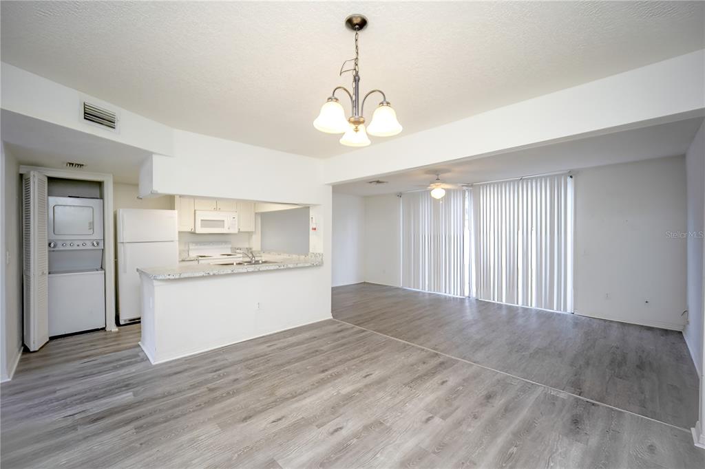 An open-concept living and dining area features light wood-look flooring and an adjacent kitchen — 811 ORCHID DRIVE, DAVENPORT, FL