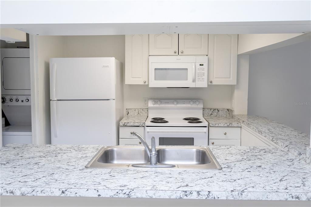 A kitchen features white appliances, granite countertops, and white cabinetry — 811 ORCHID DRIVE, DAVENPORT, FL