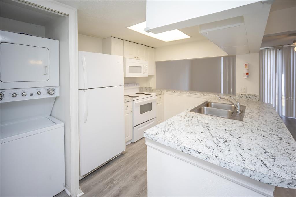 A kitchen features white appliances, granite-look countertops, and light wood-style flooring — 811 ORCHID DRIVE, DAVENPORT, FL