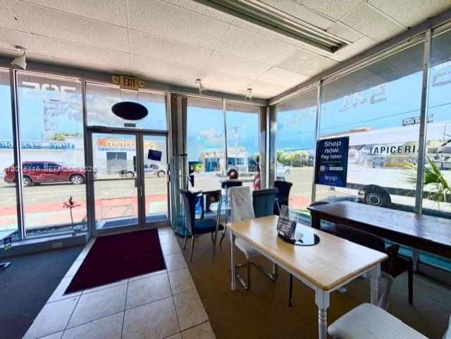 A commercial space features large windows, a glass entry door, and a light-colored table — 3100 NW 7th St, Miami FL 33125, MIAMI, FL
