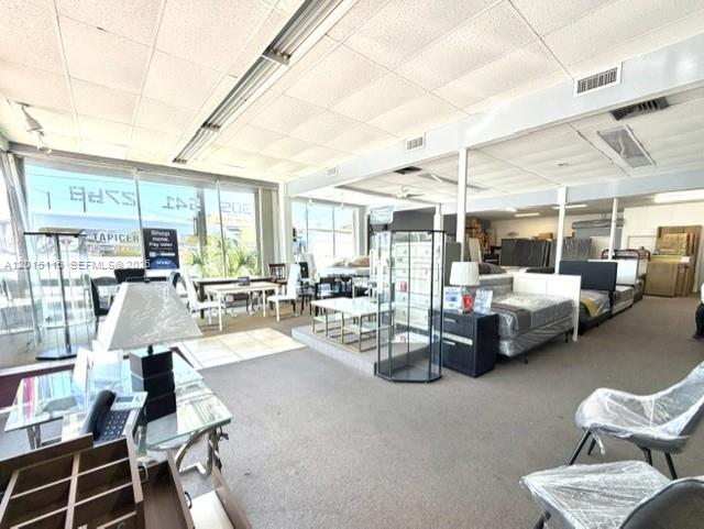 A furniture showroom features glass display tables, mattresses, and chairs under a drop ceiling — 3100 NW 7th St, Miami FL 33125, MIAMI, FL