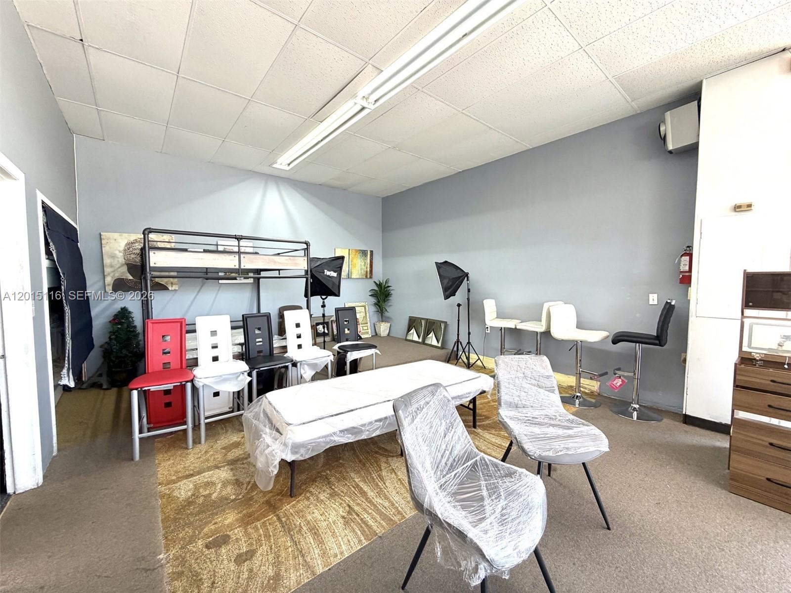 A room with gray walls, a drop ceiling, and various chairs and furniture pieces — 3100 NW 7th St, Miami FL 33125, MIAMI, FL