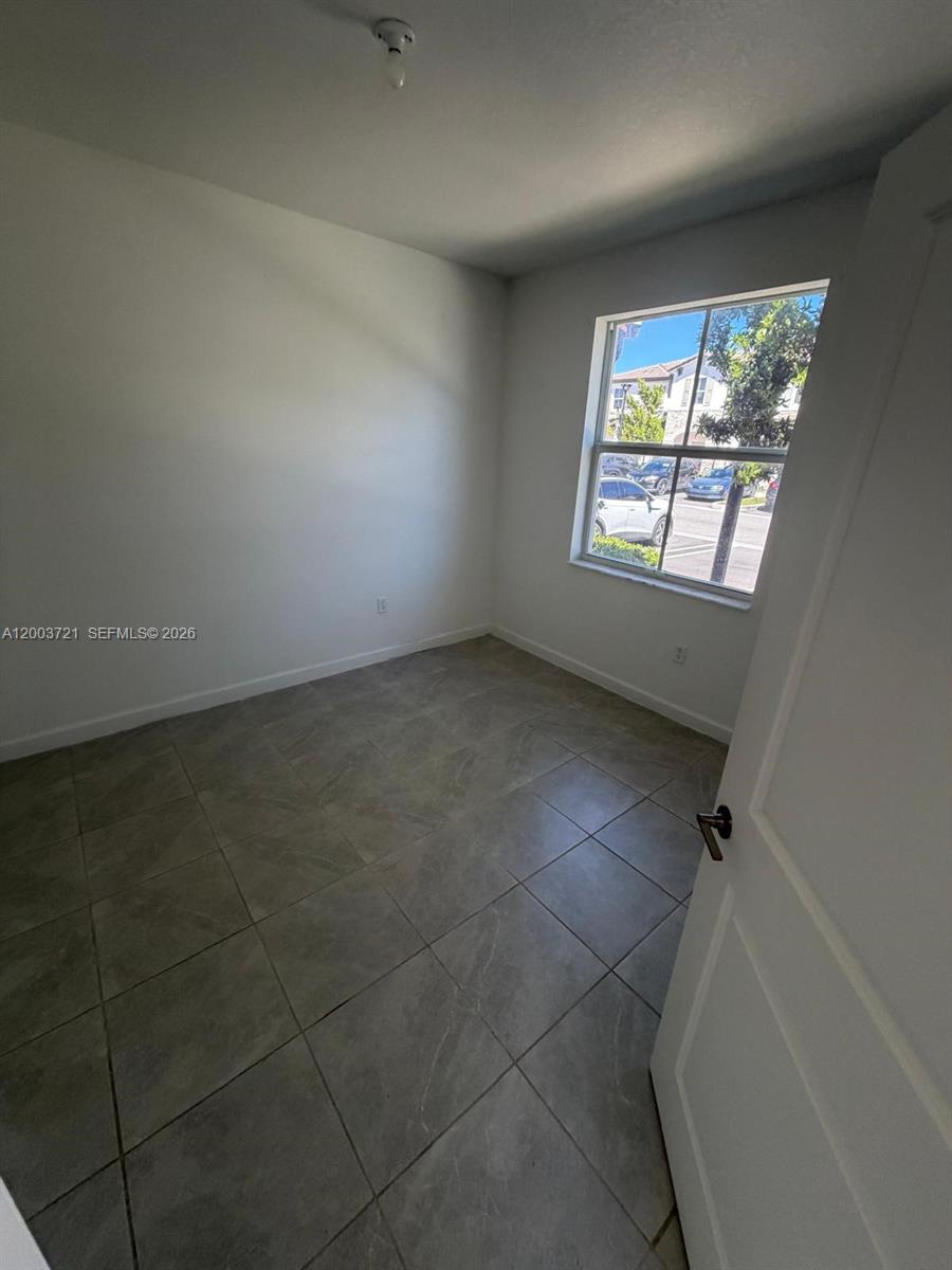 A small, empty room features white walls, gray tile flooring, and a single window — 12148 NW 24TH PL # 12148, Miami FL 33167, MIAMI, FL