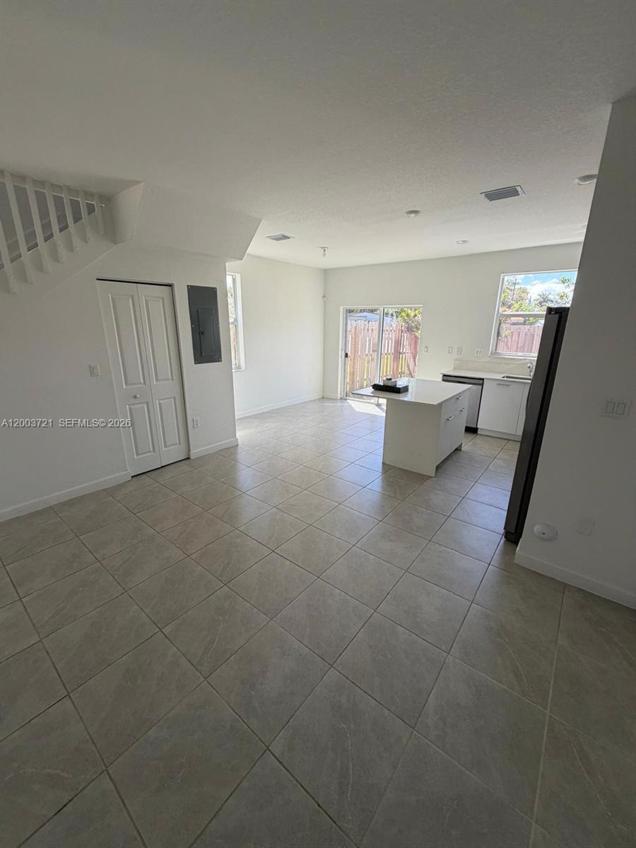 An open-concept kitchen and living area features tile flooring, a center island, and sliding doors — 12148 NW 24TH PL # 12148, Miami FL 33167, MIAMI, FL