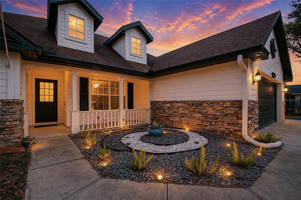 A house exterior features a stone-accented facade, a spiral rock garden, and a covered porch — 2305 JESSICA LANE, KISSIMMEE, FL