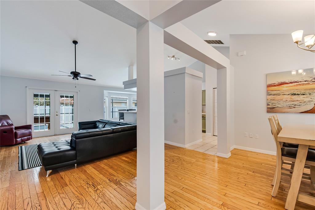 A living room and dining area feature hardwood floors, white walls, and a black sectional — 2305 JESSICA LANE, KISSIMMEE, FL