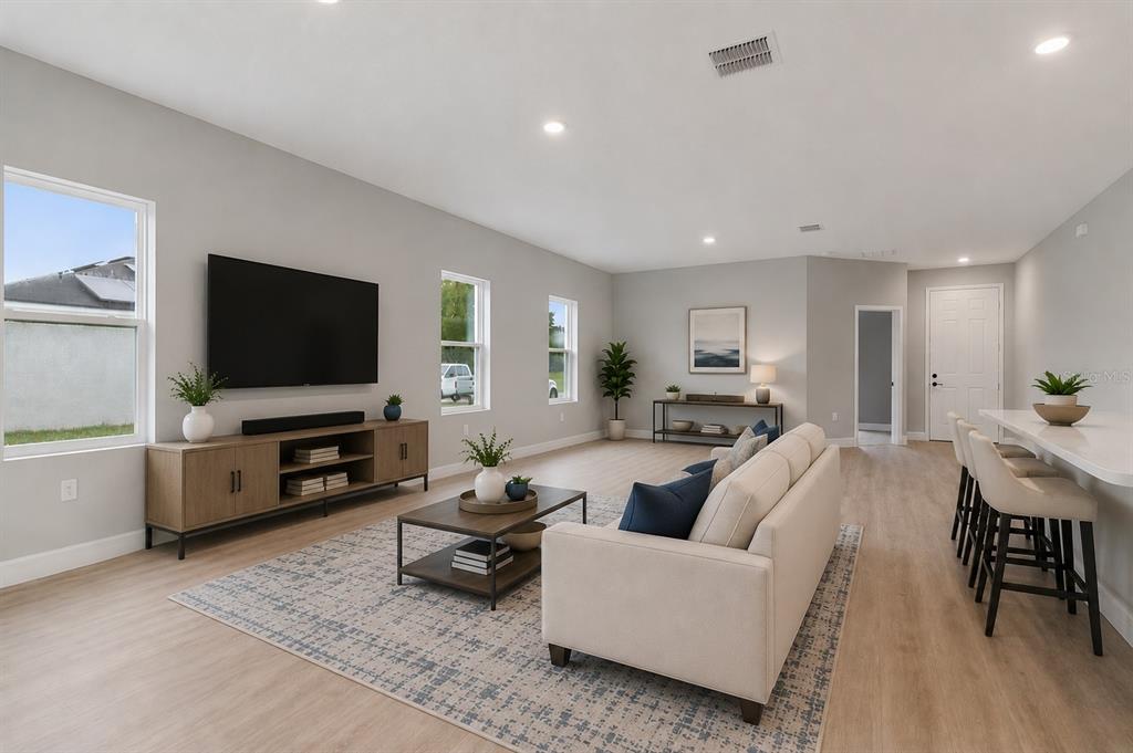 A modern living room features light wood flooring, a neutral sofa, and a television console — 489 MARION OAKS TRAIL, OCALA, FL