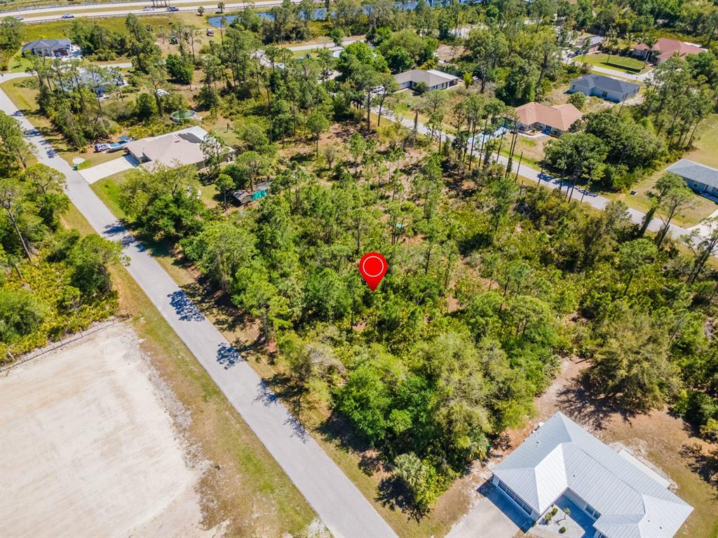 An aerial view shows a wooded, undeveloped residential lot marked by a red pin — 23309 WILBER AVENUE, PUNTA GORDA, FL