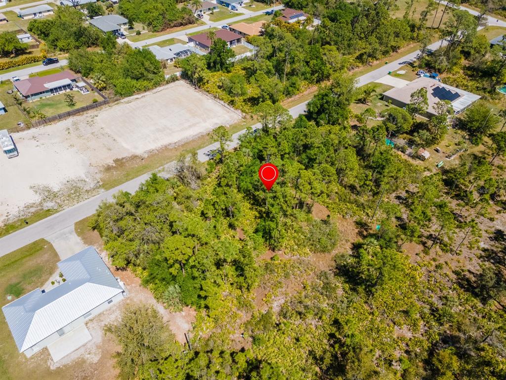 An aerial view shows a wooded, undeveloped lot marked with a red circle — 23309 WILBER AVENUE, PUNTA GORDA, FL