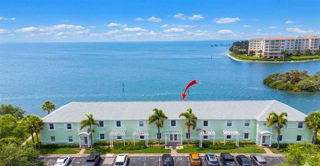 An exterior view of a waterfront apartment building with a parking lot in the foreground — 5282 BEACH DRIVE SE APT D, ST PETERSBURG, FL