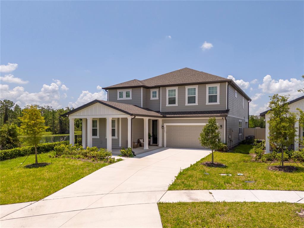 A two-story house with gray siding, a front porch, and a concrete driveway — 2184 BROADBROOK DRIVE, ST CLOUD, FL