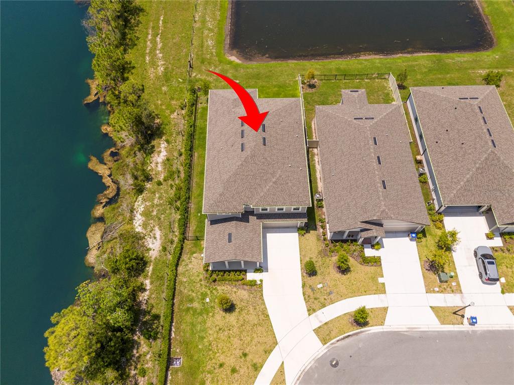 An aerial view shows a residential house with a shingled roof next to a lake — 2184 BROADBROOK DRIVE, ST CLOUD, FL