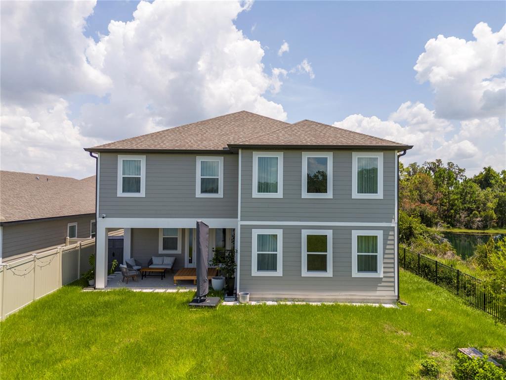 The rear exterior of a two-story gray house features a covered patio and a fenced yard — 2184 BROADBROOK DRIVE, ST CLOUD, FL